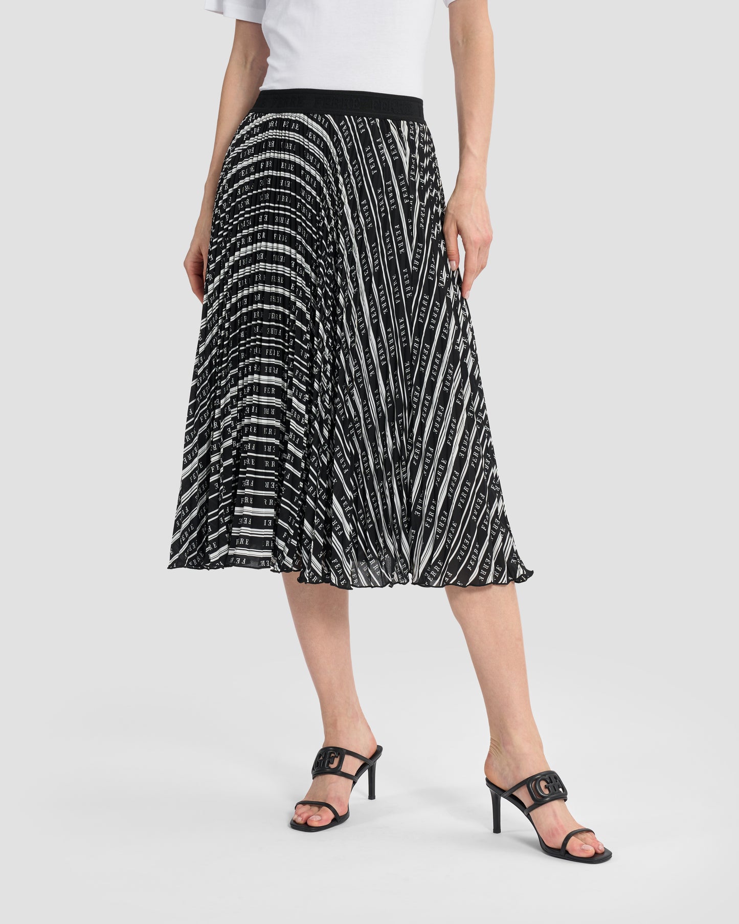 Woman wearing a Gianfranco Ferré black and white pleated midi skirt, paired with black high-heeled sandals