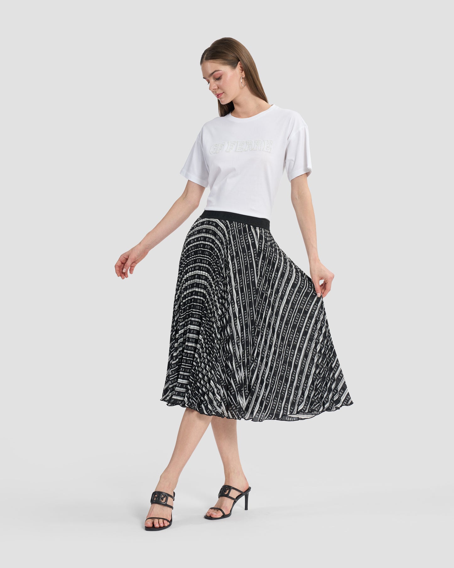 Woman wearing a Gianfranco Ferré black and white pleated midi skirt, paired with black high-heeled sandals