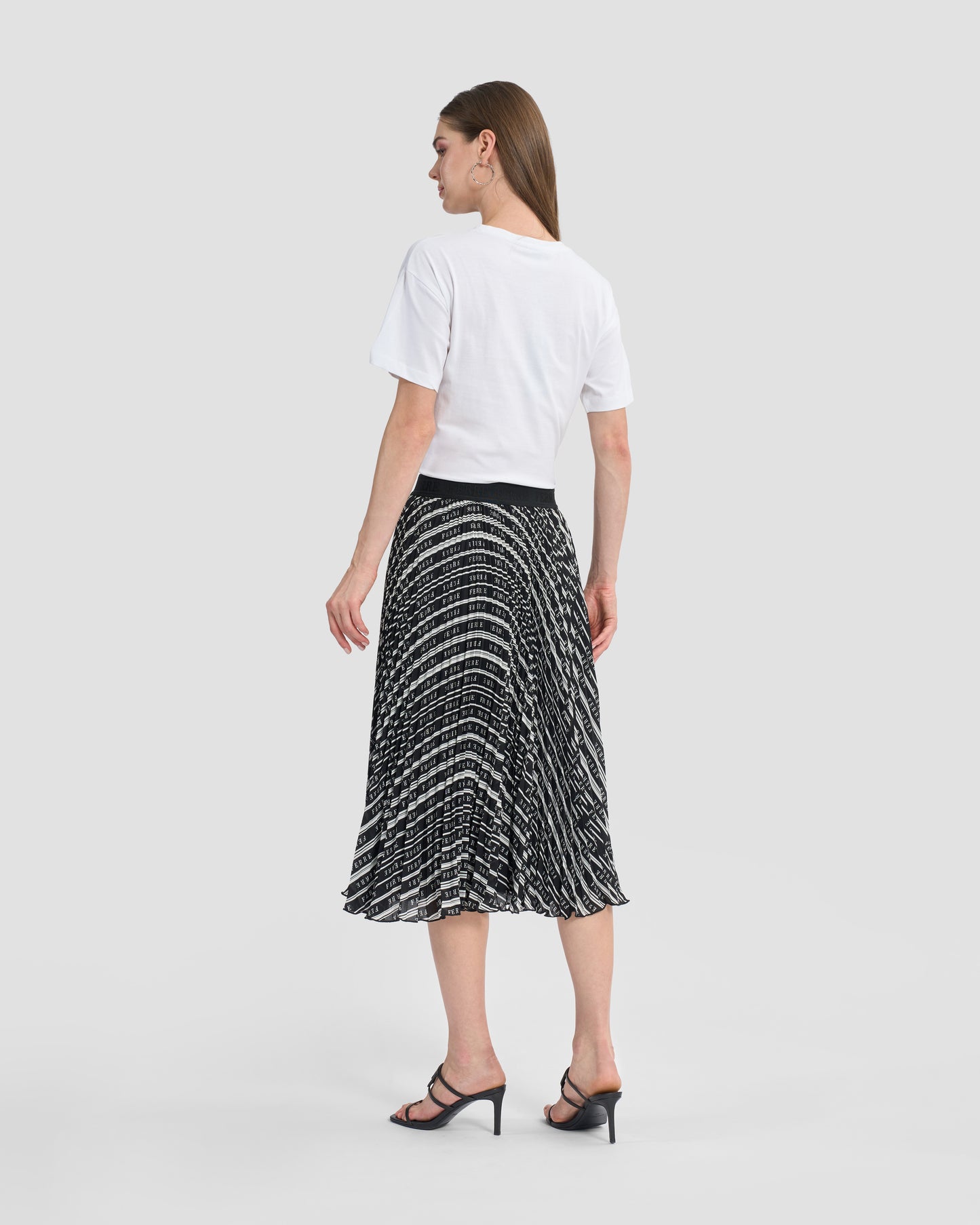 Woman wearing a Gianfranco Ferré black and white pleated midi skirt, paired with black high-heeled sandals